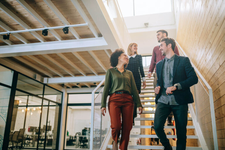 four employees talking as they walk down the stairs